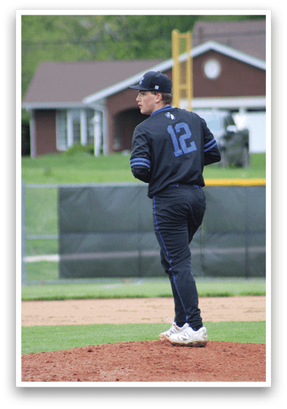 A baseball player wearing a blue and black shirt and number 12 on the back of his jersey. Description generated by AI