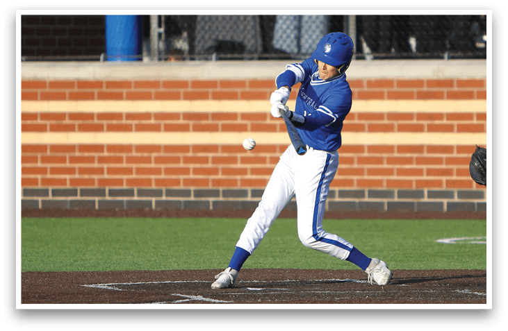 A baseball player in a blue and white uniform is swinging a bat at a ball. Description generated by AI
