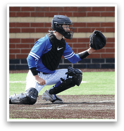 A baseball player in a blue shirt and black helmet is crouching down to catch a ball. Description generated by AI
