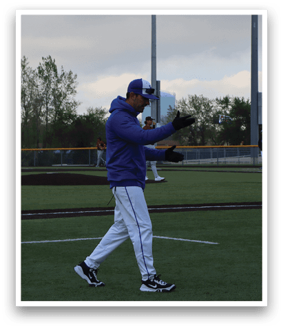 A man wearing a blue jacket and white pants is walking on a baseball field. Description generated by AI