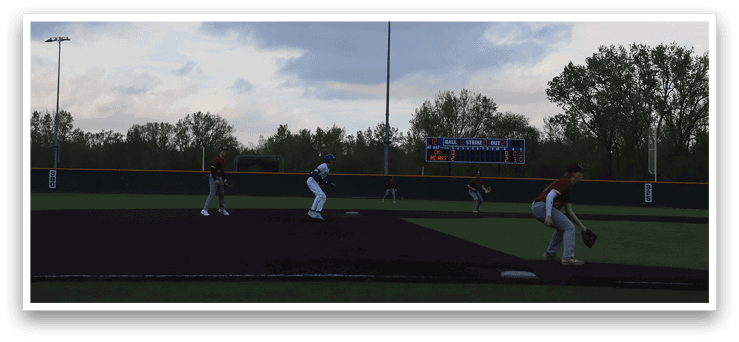 A baseball game is being played on a field with a blue sky in the background. Description generated by AI
