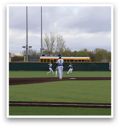 A baseball field with a player standing in the outfield. Description generated by AI