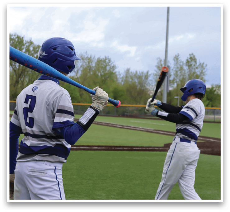 Two baseball players on a field, one holding a bat and the other holding a bat. Description generated by AI