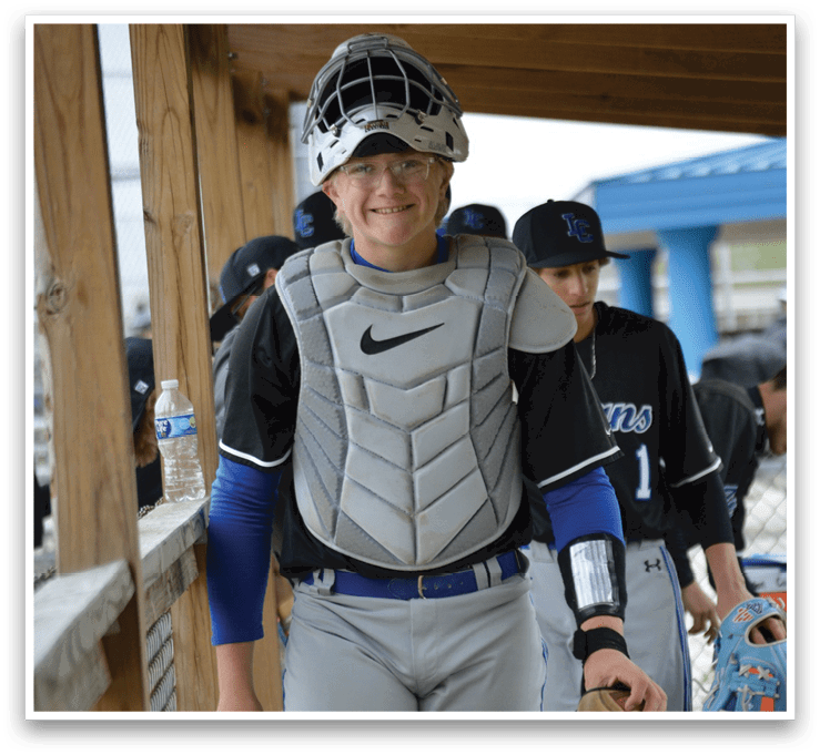 A boy wearing a baseball uniform and a helmet. Description generated by AI