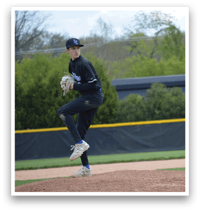 A baseball player in a black shirt and blue shoes is pitching a ball. Description generated by AI