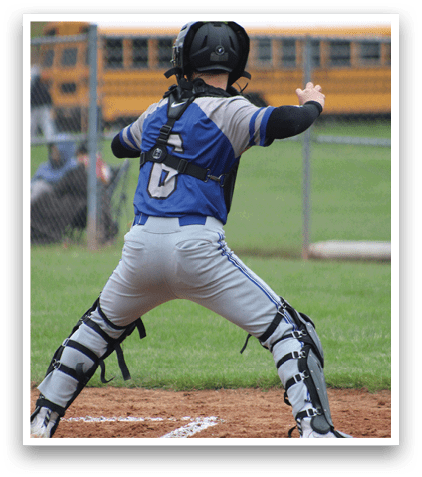 A baseball player in a blue and grey uniform is in the catcher's position. Description generated by AI