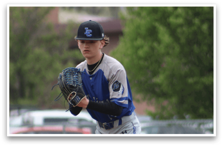 A baseball player in a blue and grey uniform is standing on the pitcher's mound. Description generated by AI