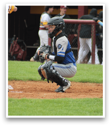 A baseball player wearing a blue shirt and white pants is kneeling on the ground. Description generated by AI
