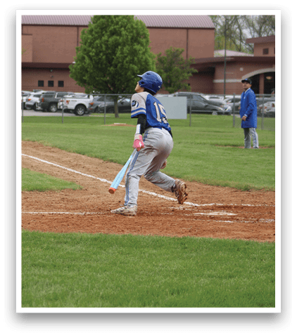 A boy is swinging a bat on a baseball field. Description generated by AI