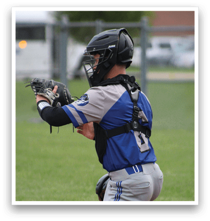 A baseball player in a blue and grey uniform is squatting down and holding a baseball glove. Description generated by AI