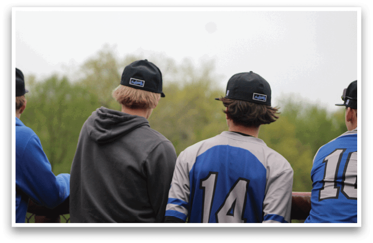 A group of young men wearing baseball caps and jerseys. Description generated by AI