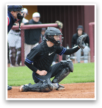 A baseball catcher wearing a black and blue uniform. Description generated by AI