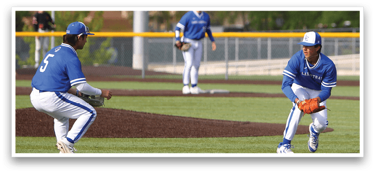 A baseball player in a blue shirt and white pants is kneeling on the ground. Description generated by AI
