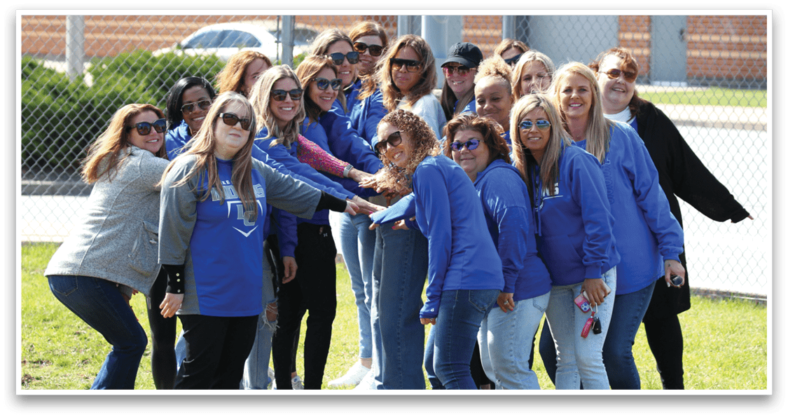 A group of women wearing blue shirts and jeans. Description generated by AI