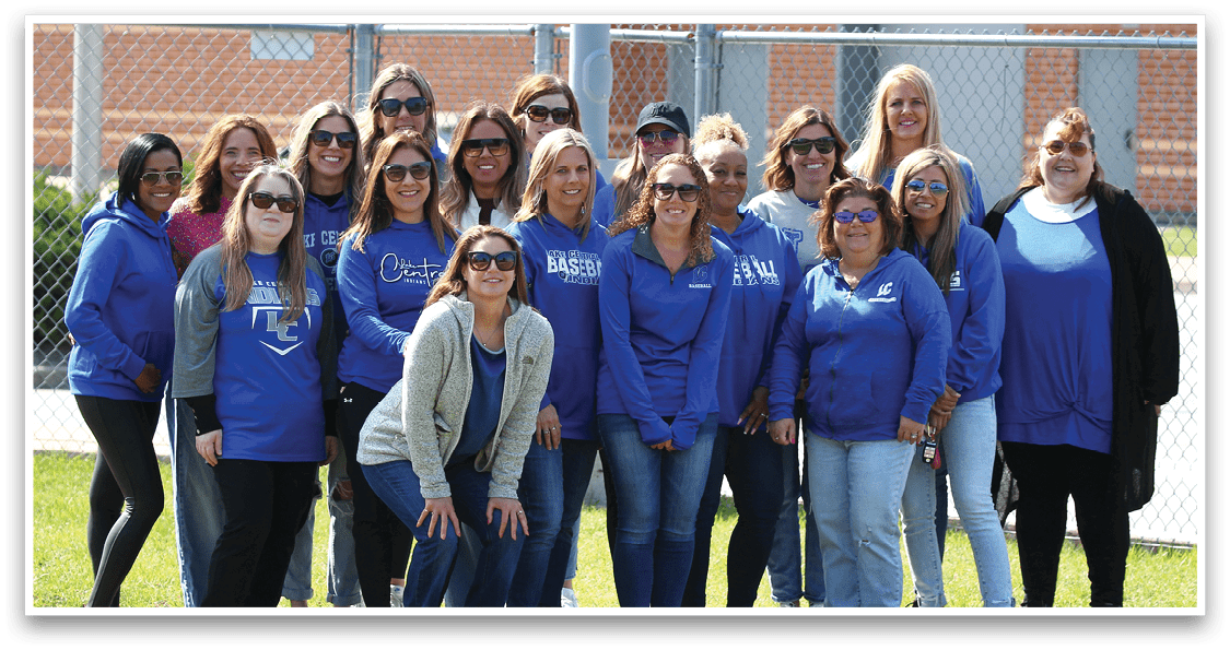 A group of women wearing blue shirts and sunglasses pose for a picture. Description generated by AI