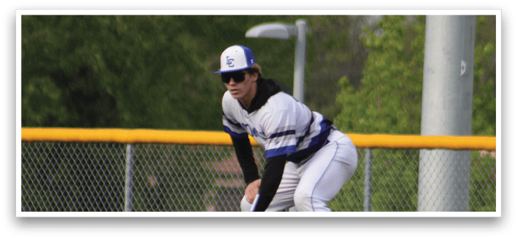A baseball player in a white uniform is crouching on the field. Description generated by AI