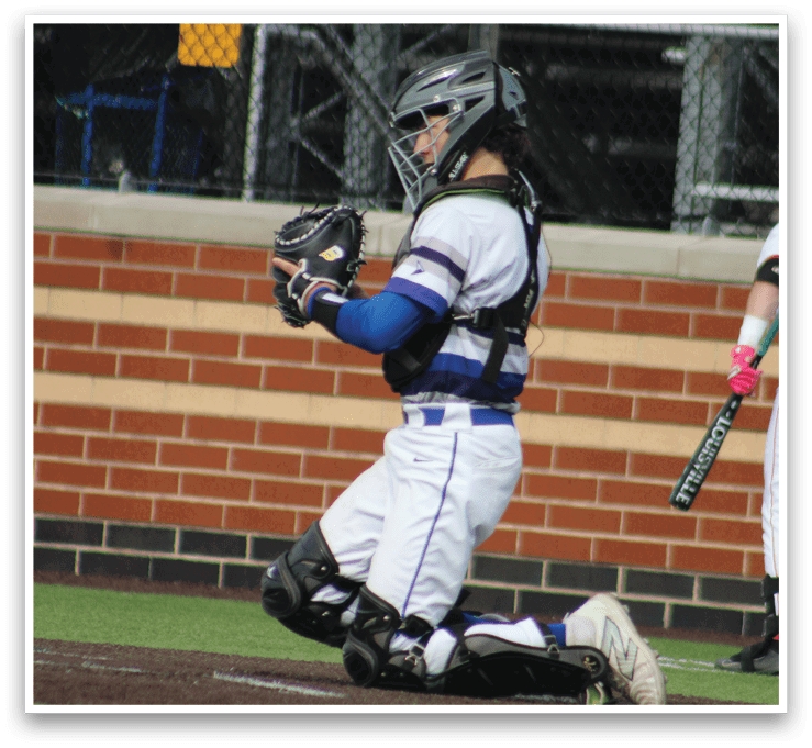 A baseball player in a blue and white uniform catching a ball. Description generated by AI