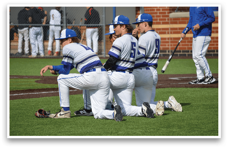 Four baseball players kneeling on the field. Description generated by AI