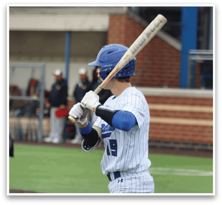 A baseball player in a blue helmet and white uniform holding a bat. Description generated by AI
