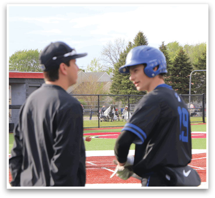 Two men standing on a baseball field. Description generated by AI
