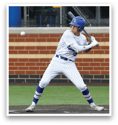 A baseball player in a white and blue uniform is swinging a bat at a ball. Description generated by AI