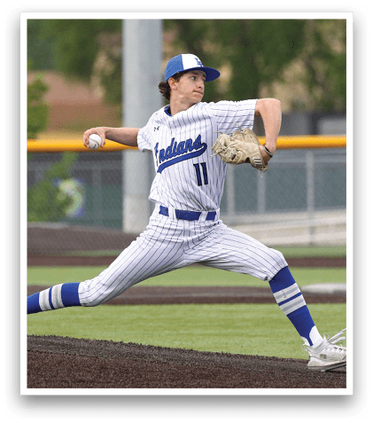 A baseball player in a white and blue uniform is pitching a ball. Description generated by AI