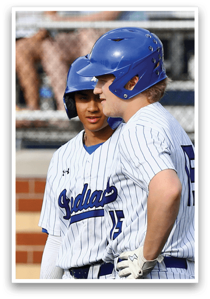 Two baseball players wearing blue helmets and white and blue uniforms. Description generated by AI