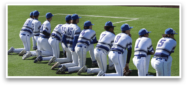 A group of baseball players in blue and white uniforms kneeling on the field. Description generated by AI