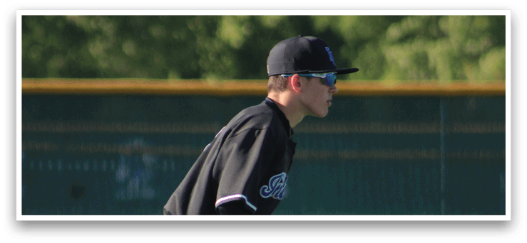 A baseball player in a black and white uniform is bending over to catch a ball. Description generated by AI