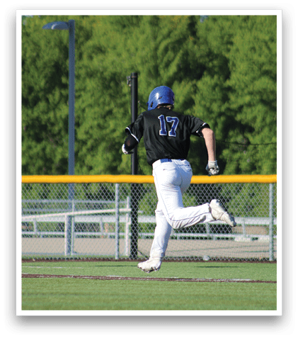A baseball player wearing a blue helmet and white uniform is running to first base. Description generated by AI