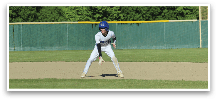 A baseball player in a blue helmet and white uniform is crouching on the field. Description generated by AI