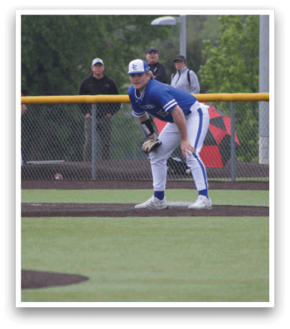 A baseball player in a blue shirt and white pants is standing on the pitcher's mound. Description generated by AI