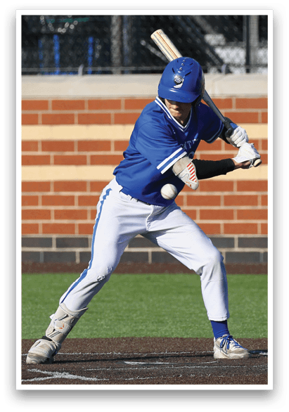 A baseball player in a blue and white uniform is swinging a bat at a ball. Description generated by AI