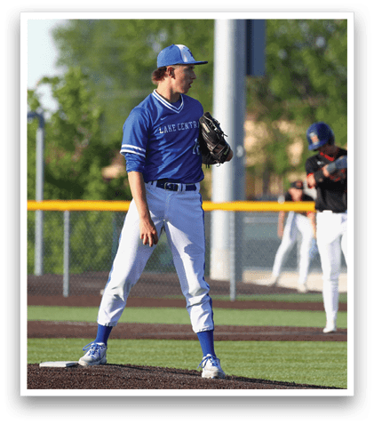 A baseball player wearing a blue shirt and white pants is standing on the pitcher's mound. Description generated by AI