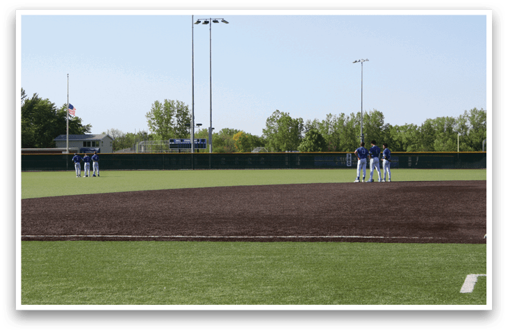 A baseball field with a group of people standing on it. Description generated by AI