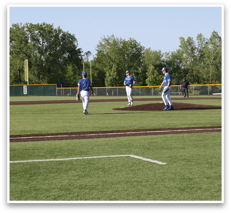 A baseball field with three men standing on it. Description generated by AI