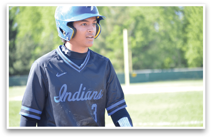 A baseball player wearing a blue helmet and a black jersey with the word Indian on it. Description generated by AI