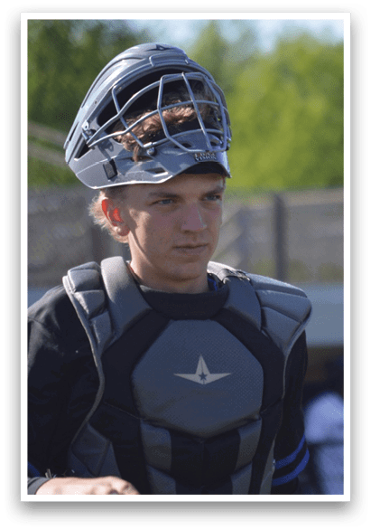 A young man wearing a baseball helmet and chest protector. Description generated by AI
