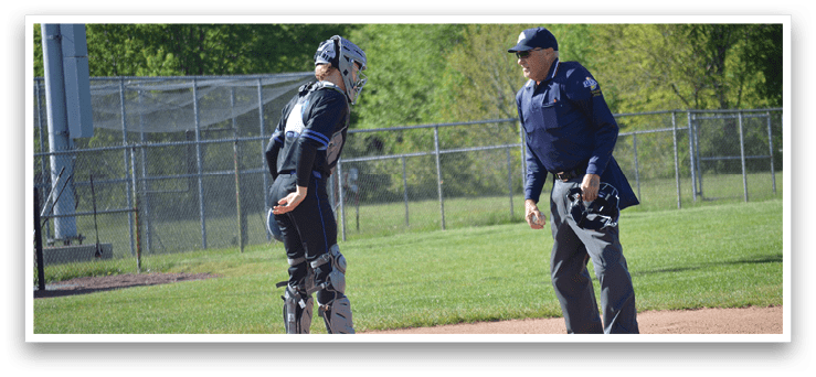 A baseball player wearing a black and blue uniform is talking to an umpire. Description generated by AI