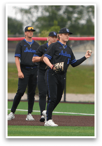 A baseball player in a blue and black uniform is holding a baseball glove. Description generated by AI