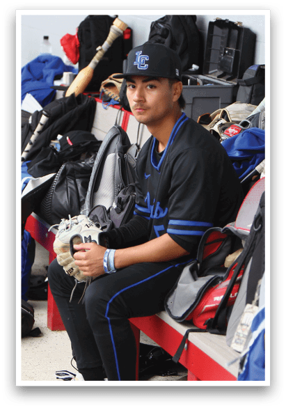 A baseball player sits on a bench with a baseball glove on his lap. Description generated by AI