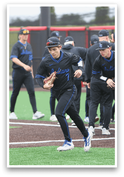 A baseball player wearing a blue and black uniform is holding a baseball glove. Description generated by AI