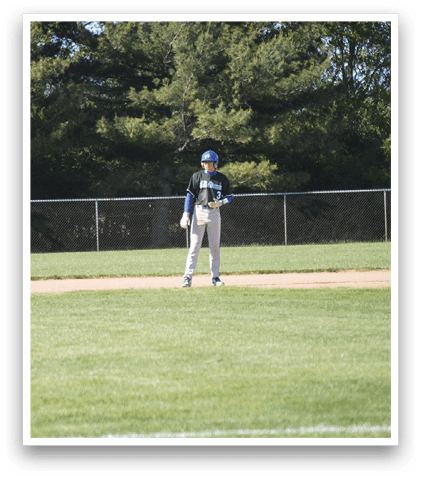 A baseball player in a blue helmet and grey uniform is standing on the field. Description generated by AI