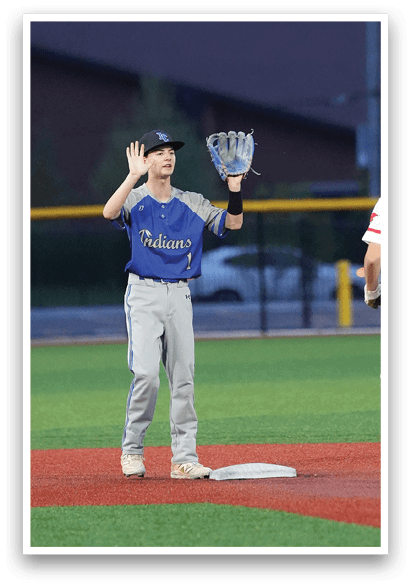 A baseball player wearing a blue shirt and grey pants holding a catcher's mitt. Description generated by AI