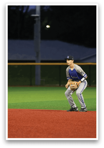 A baseball player in a grey uniform is crouching on the field. Description generated by AI