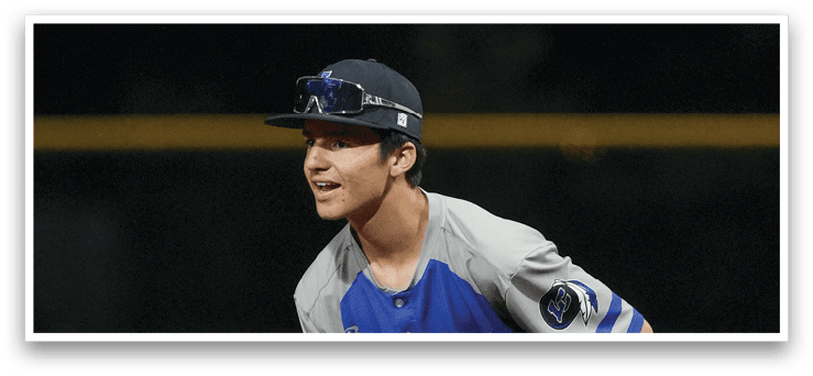 A baseball player in a blue and grey uniform is squatting on the field. Description generated by AI