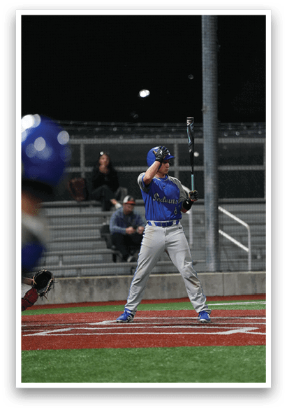 A baseball player in a blue and white uniform is holding a bat and getting ready to swing. Description generated by AI
