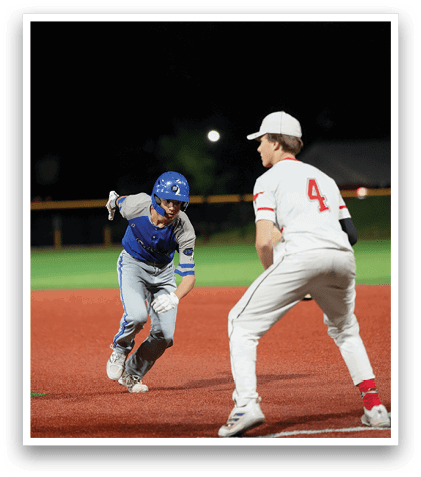 A baseball player wearing a blue helmet and grey uniform is running towards a base. Description generated by AI