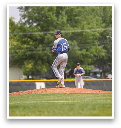 A baseball player wearing a blue and white uniform is standing on a mound. Description generated by AI