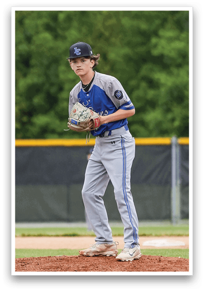 A baseball player in a blue and gray uniform stands on a pitcher's mound. Description generated by AI
